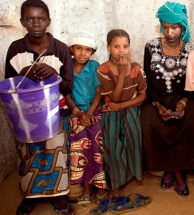 NIGER. Tajae. Khadijatou, Tuareg wife of the ex-chief of Tajae in the Tuareg palace with royal daughters Aminatou and Fatima and slave holding a bucket. 2005.